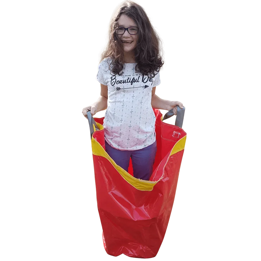 Lachend meisje staat in een rode zaklopen zak met gele rand en houdt de twee handgrepen vast.