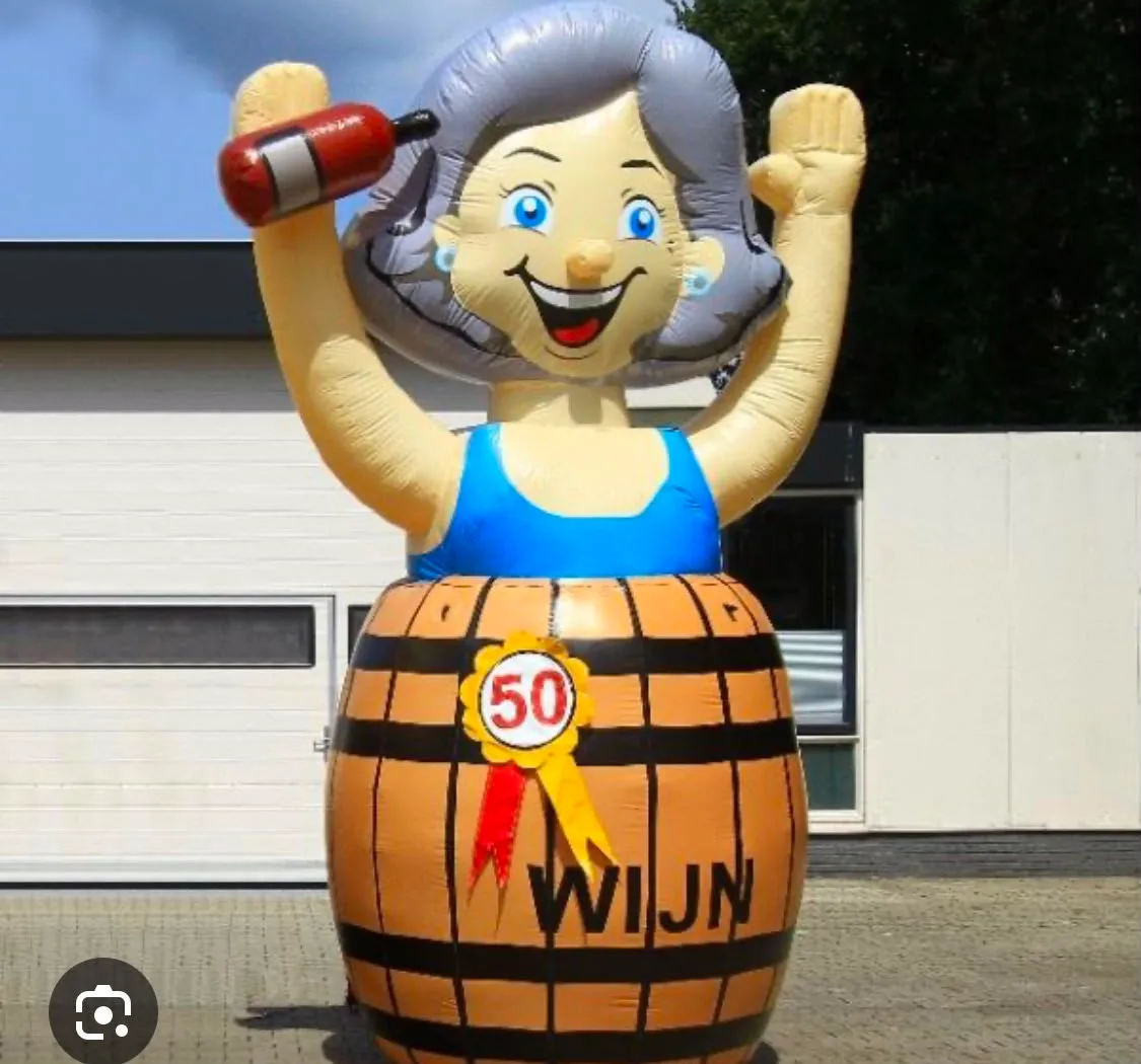 Opblaasbare Sarah feestpop van 3,5 meter in een wijnvat met rosette met het getal 50, opgesteld voor het pand van Opblaaswereld de Blok.