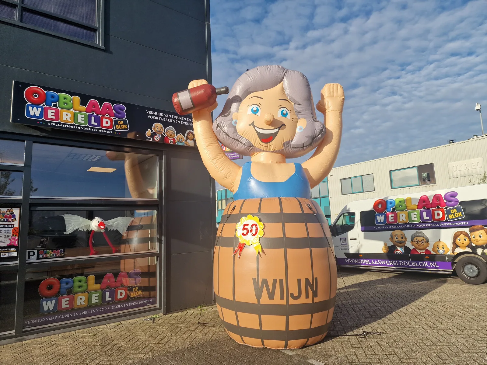 Opblaasbare Sarah feestpop van 3,5 meter in een wijnvat met rosette met het getal 50, Opblaaswereld de Blok.